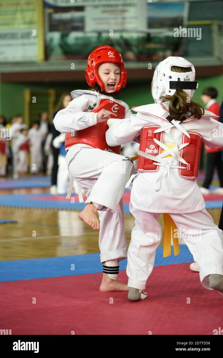 Niñas de siete años compitiendo en un torneo de Taekwondo con un dobok y equipo protector. Foto de stock