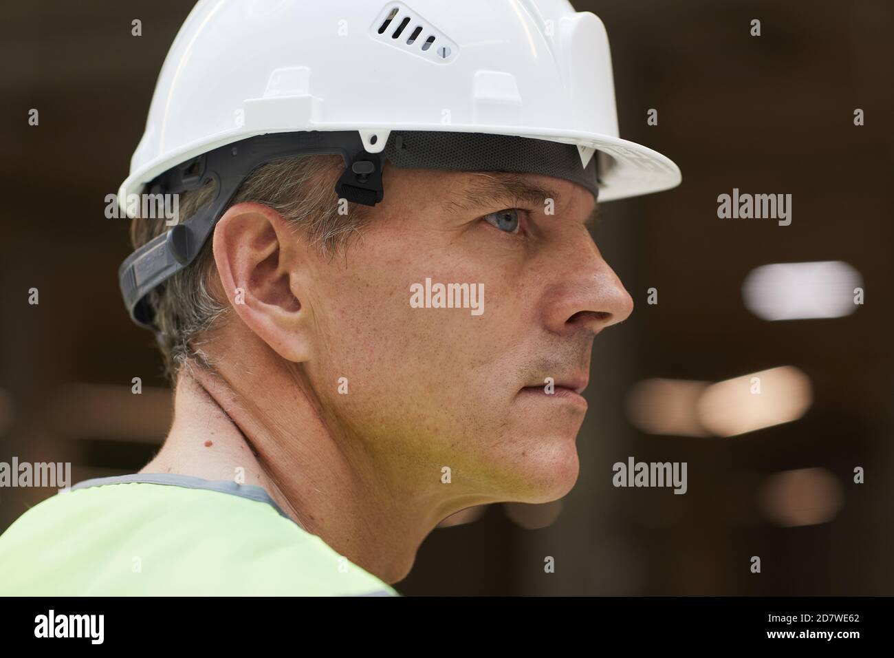 Vista lateral retrato de un trabajador profesional de la construcción que lleva casco y mirando hacia fuera, espacio de copia Foto de stock