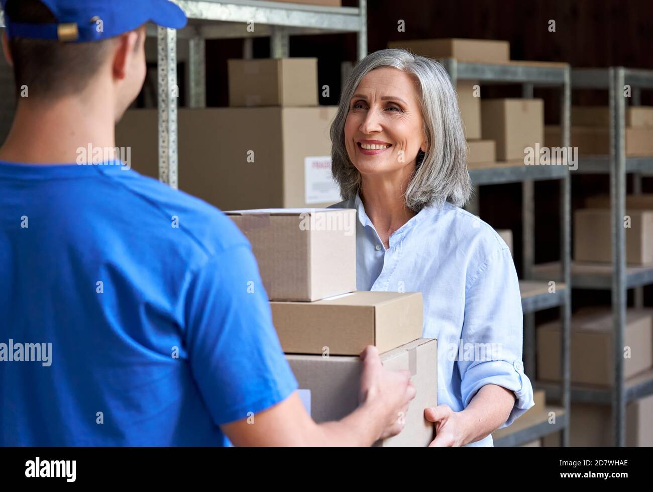 Feliz Mujer Madura Gerente Dando Paquetes Cajas Al Mensajero En El Almacén Fotografía De Stock 5449