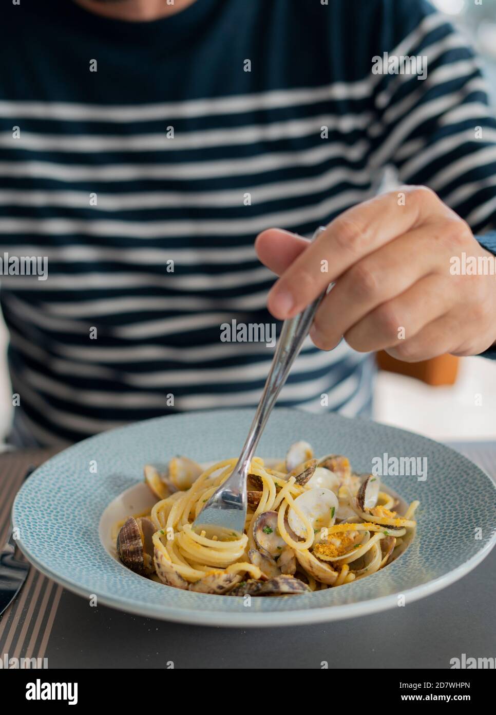 Detalle macho comer a mano pasta espaguetis con almejas y salmonetes, comida mediterránea Foto de stock