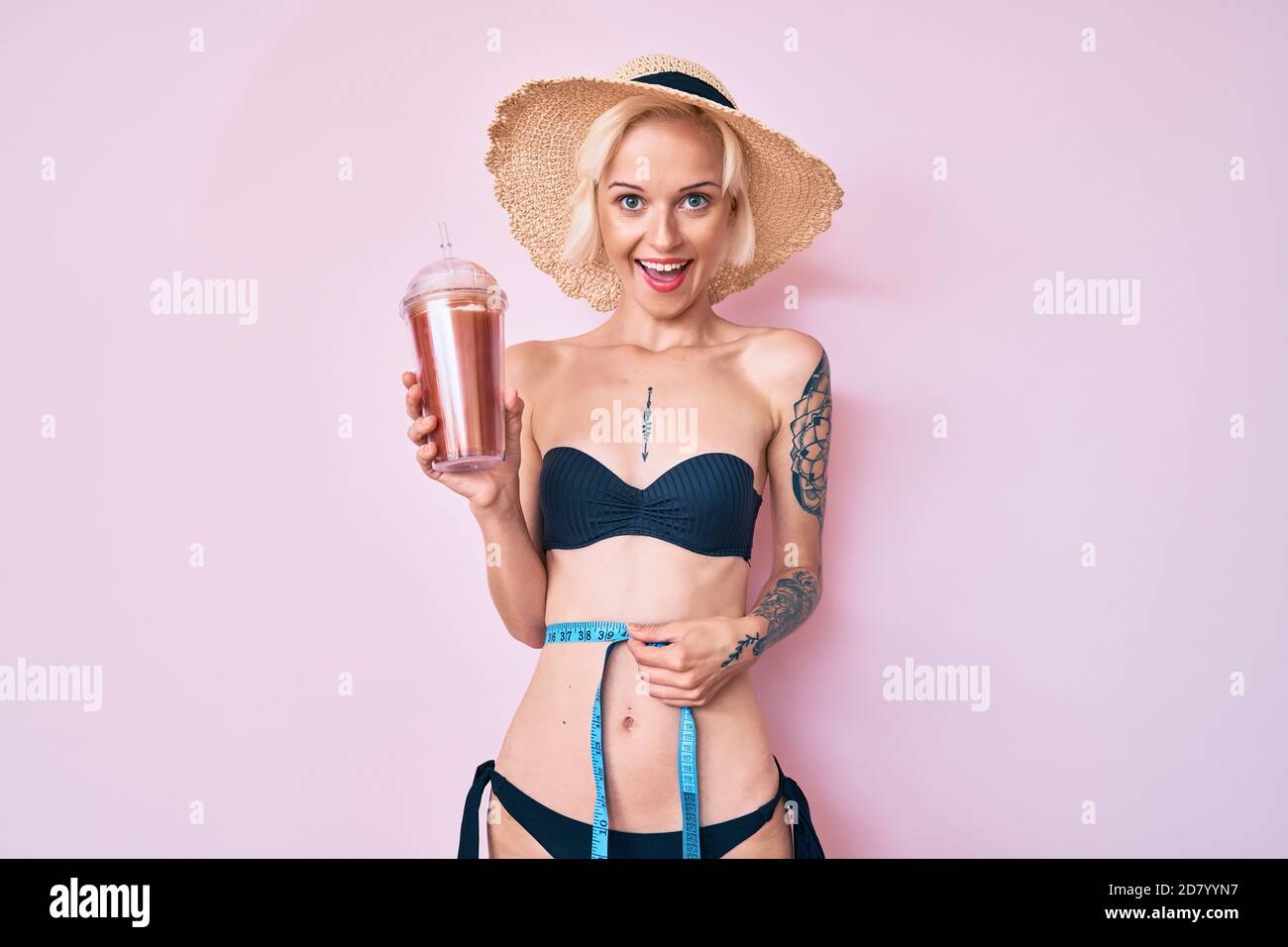 Joven rubia mujer con tatuaje usando bikini con cinta de medir y beber  smoothie sonriendo y riendo fuerte, porque divertido chiste loco Fotografía  de stock - Alamy