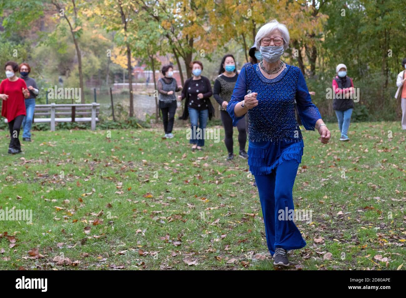 Un grupo de mujeres asiáticas americanas de todas las edades usan máscaras y socialmente a distancia. En una clase de ejercicios de baile en un parque en Flushing, Queens, Nueva York. Foto de stock
