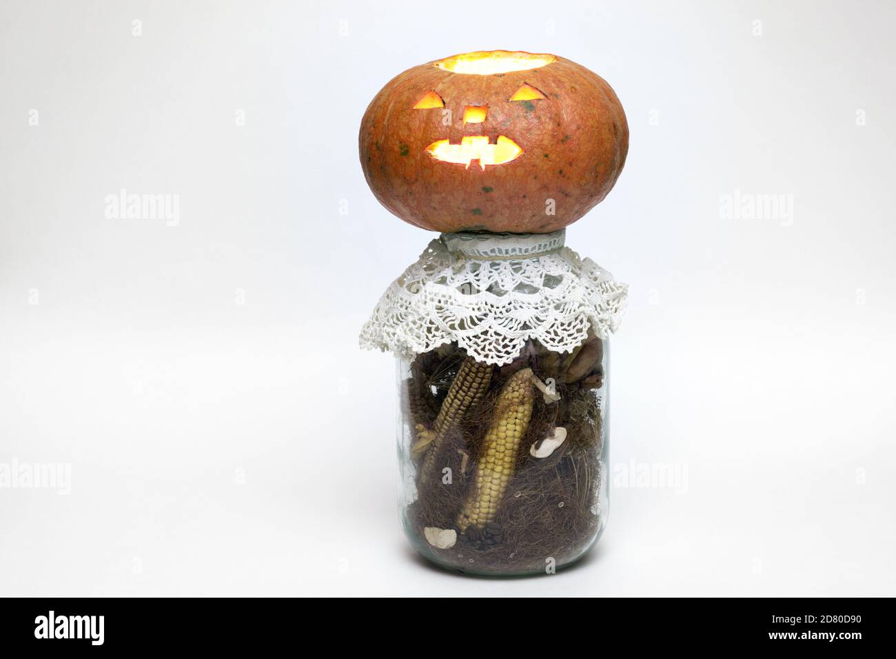 calabaza de halloween en una botella llena de maíz seco y estigmas de maíz. cara tallada en calabaza vacía con linterna de vela en el interior Foto de stock