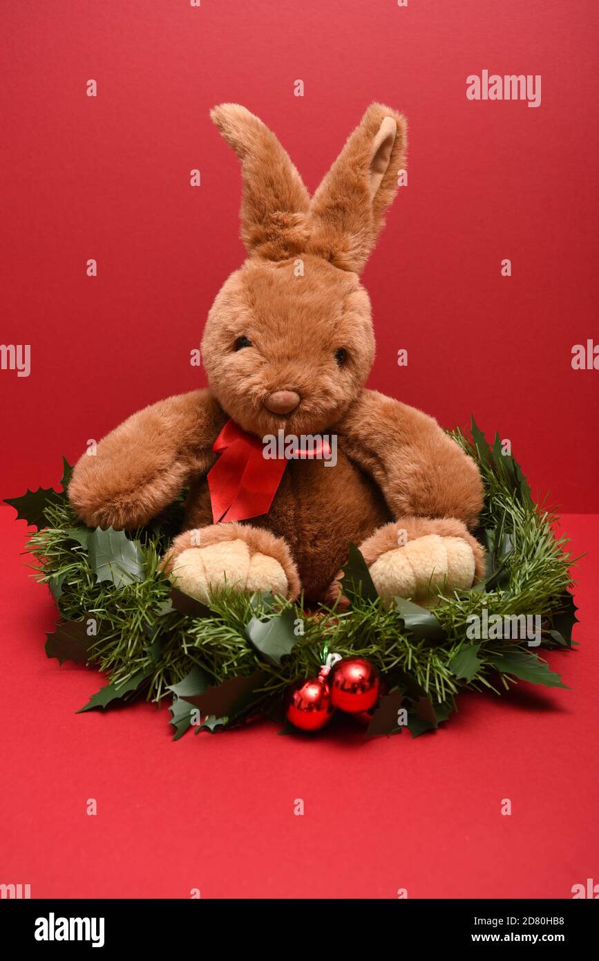 Conejo de juguete sentado en una guirnalda de Navidad en un retrato Foto de stock