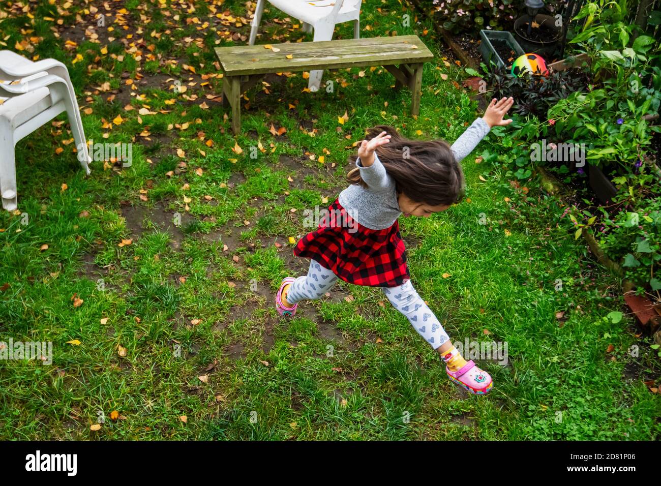 Niño pequeño saltando en la temporada de otoño en el patio trasero Foto de stock