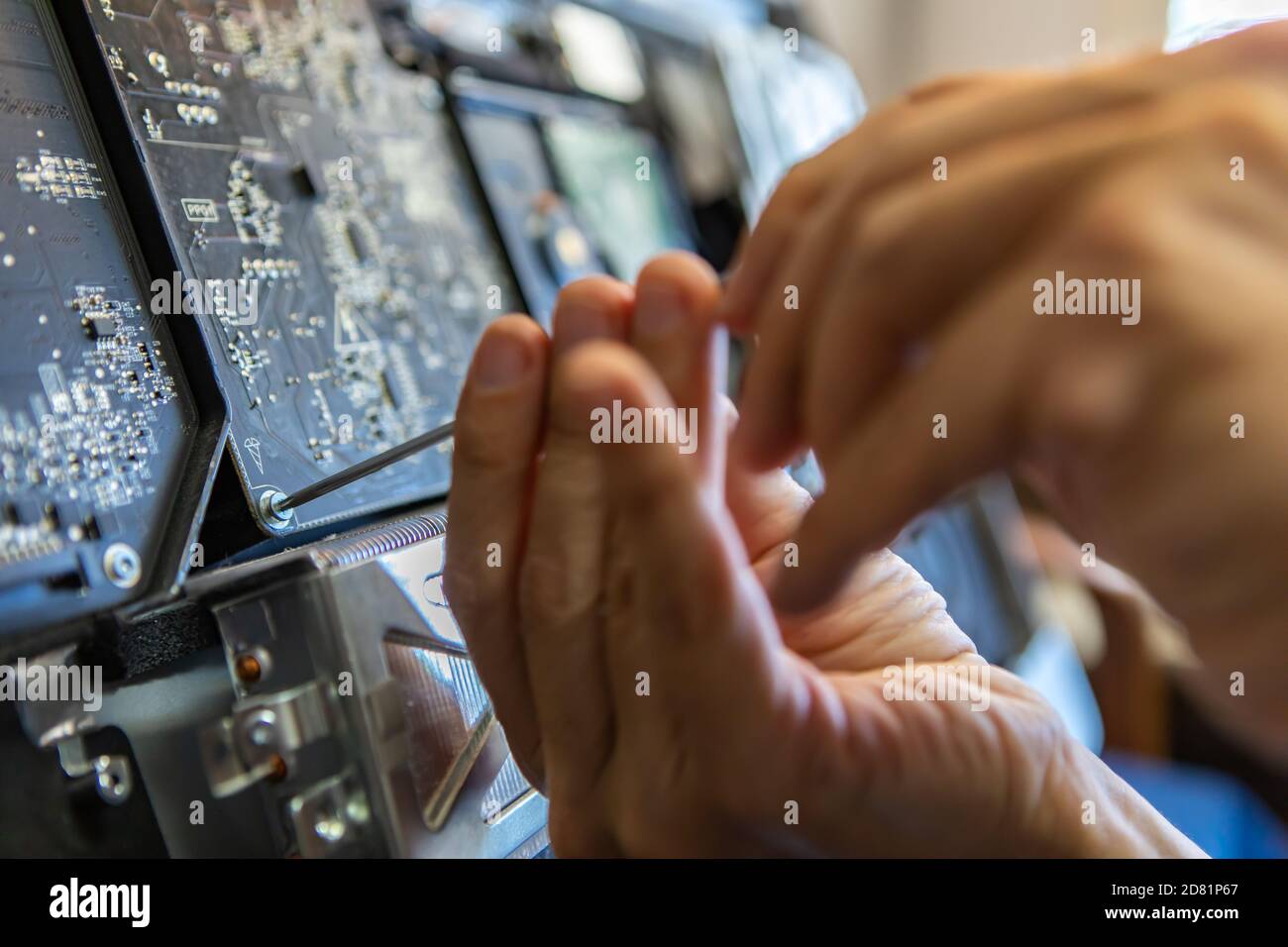 Enfoque selectivo de manos de técnico macho desatornillando pernos para analizar problema con el equipo roto y resolverlo para un funcionamiento suave Foto de stock