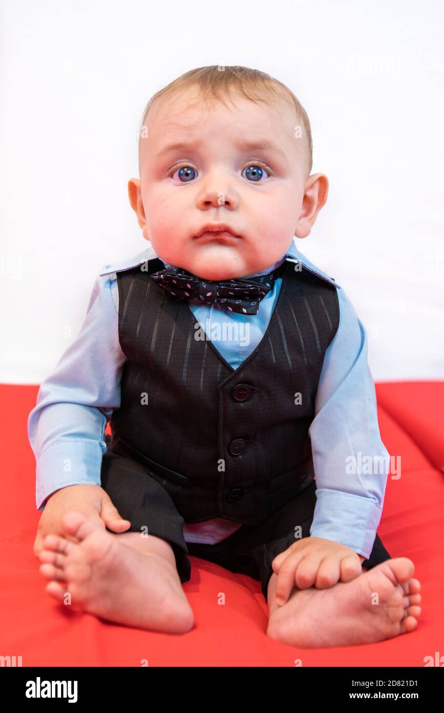 Retrato de un bebé lindo con ropa formal sentado ropa roja y posando para aislada contra fondo llano Fotografía de stock - Alamy