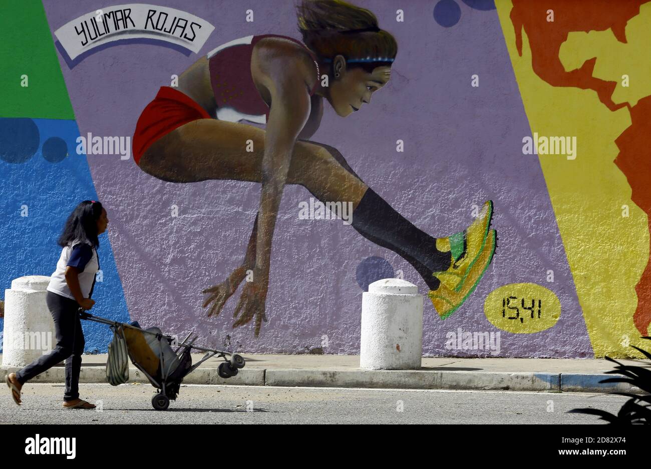 Valencia Carabobo Venezuela 26 De Octubre De Pie De Foto 26 De Octubre De Awoman Llevando Agua En Un Carro De Bebe Camina Delante De Un Graffiti Del Atleta Venezolano