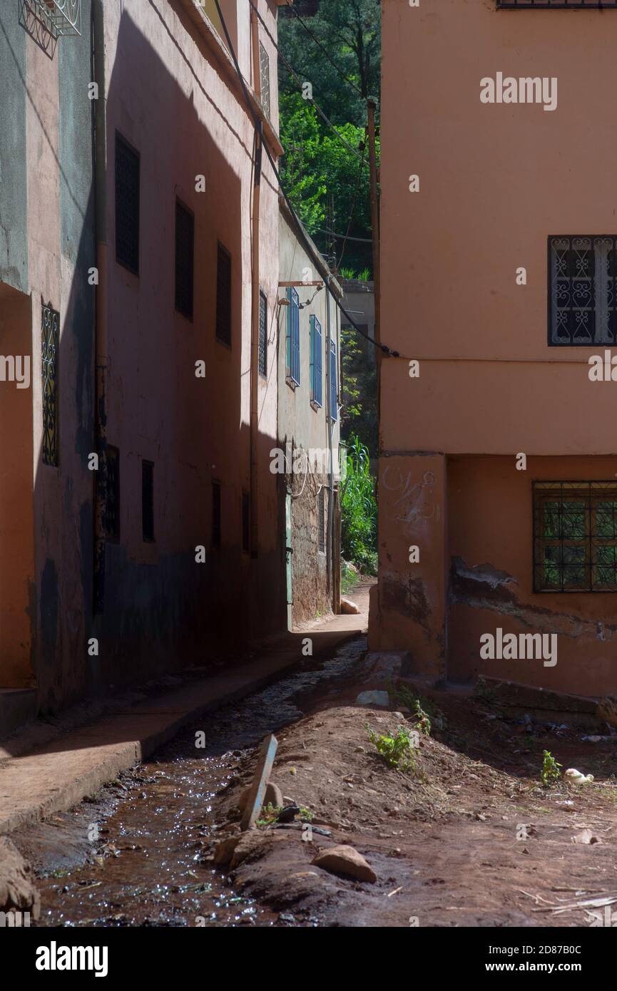 Calle estrecha con sencillas casas de colores enyesados en Setti Fatma, en el valle de Ourika, cerca de Marrakech, Marruecos. El agua turbia de las montañas corre Foto de stock