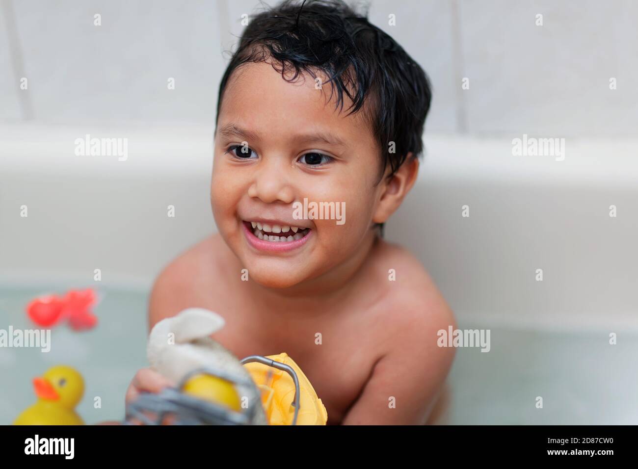 Un niño que se divierte y se ríe durante el baño y juega con los juguetes de baño para niños pequeños. Foto de stock