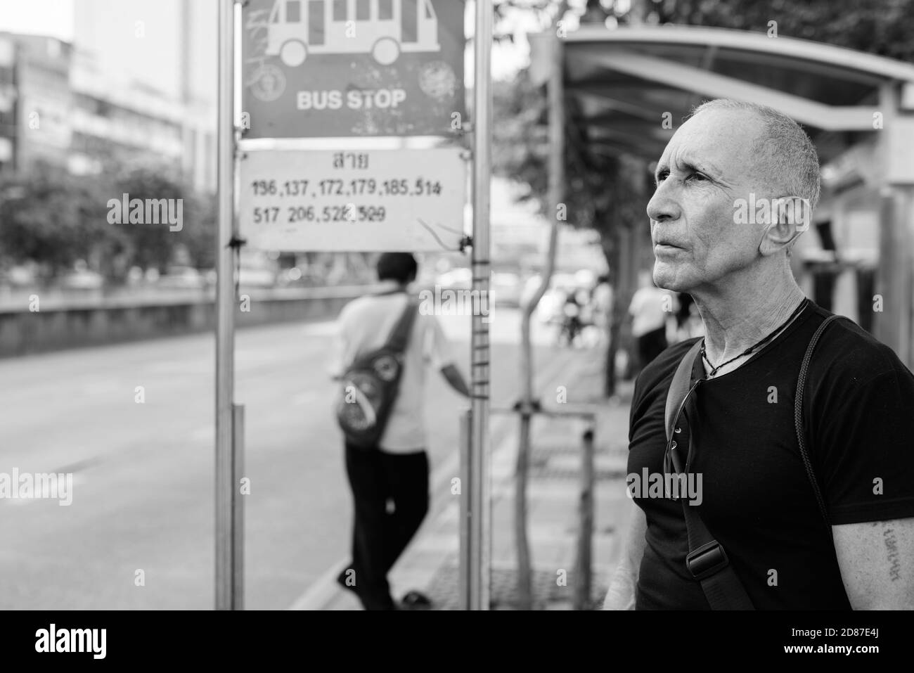 Turismo Senior calva hombre pensando mientras espera en la parada del autobús, en Bangkok, Tailandia Foto de stock