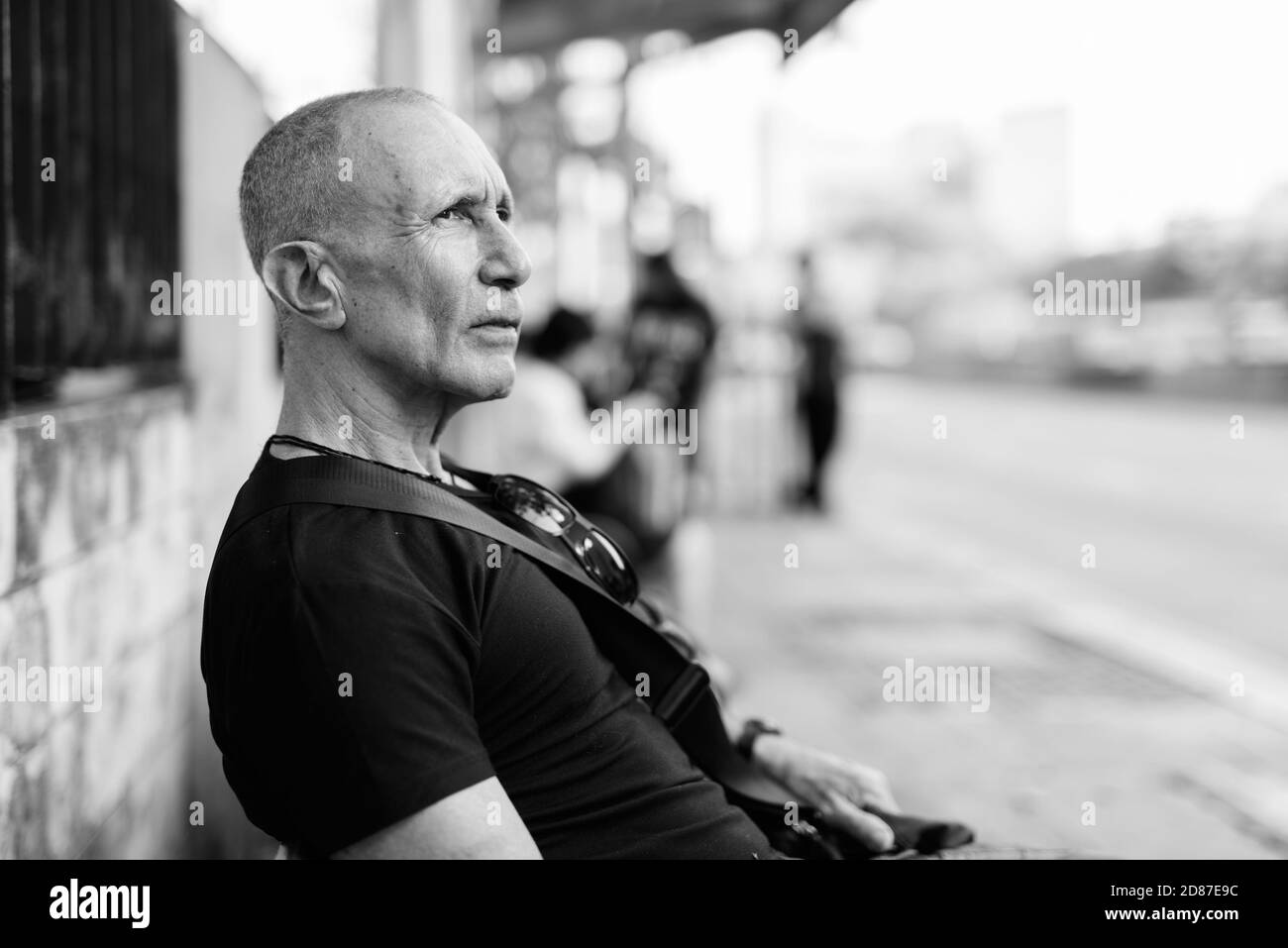 Ver perfil de turista senior calva hombre pensando mientras espera en la parada del autobús, en Bangkok, Tailandia Foto de stock