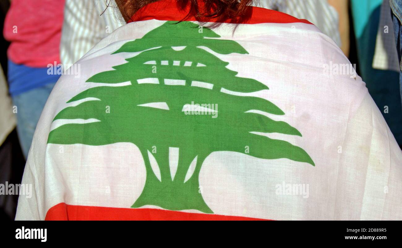 La bandera libanesa con el cedro está envuelta alrededor de una mujer en un rally en Beirut, Líbano. Foto de stock