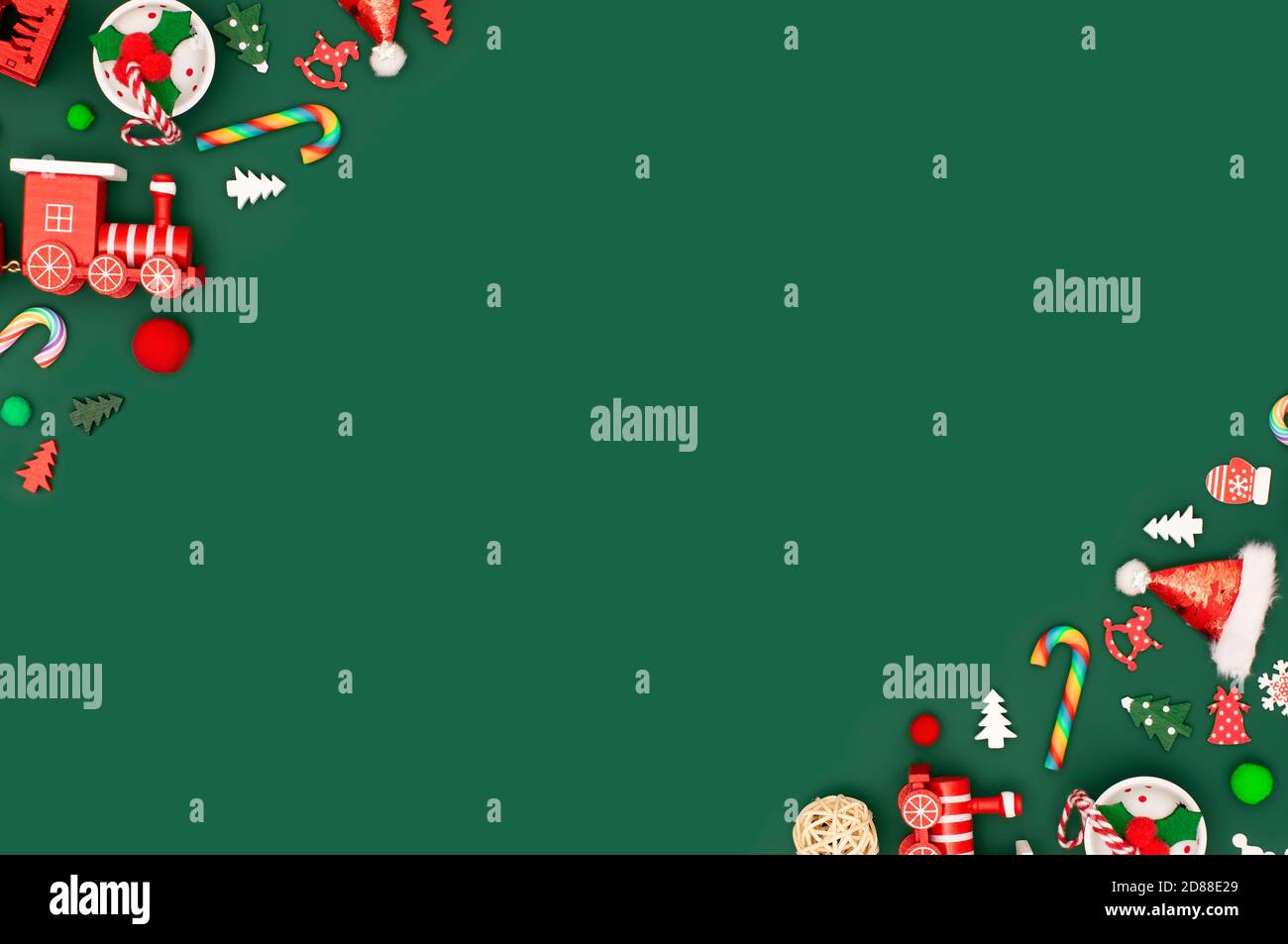 Fondo verde de Navidad o año Nuevo con bordes de juguetes rojos diagonales. Juguetes tradicionales y retro en las esquinas. Campanas, cañas de lollipop, copos de nieve Foto de stock
