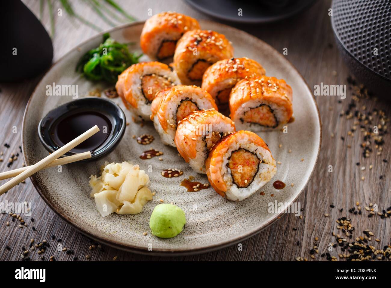 Rollitos de sushi al horno con salmón, cangrejo y salsa picante en un plato  con palillos, salsa de soja, wasabi y jengibre. Pescado japonés tradicional  Fotografía de stock - Alamy