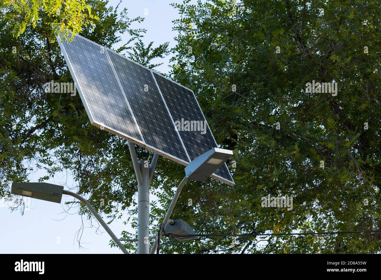 Energía solar alternativa. Dispositivo solar con lámpara de calle sobre  fondo de cielo azul y árbol verde. Luz de calle alimentada por panel solar  con batería Inc Fotografía de stock - Alamy