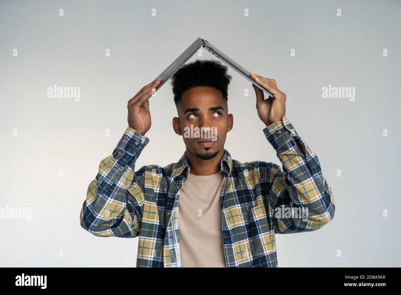 Un empresario frustrado está llevando un ordenador portátil sobre su cabeza. Aislado sobre fondo blanco. Foto de stock