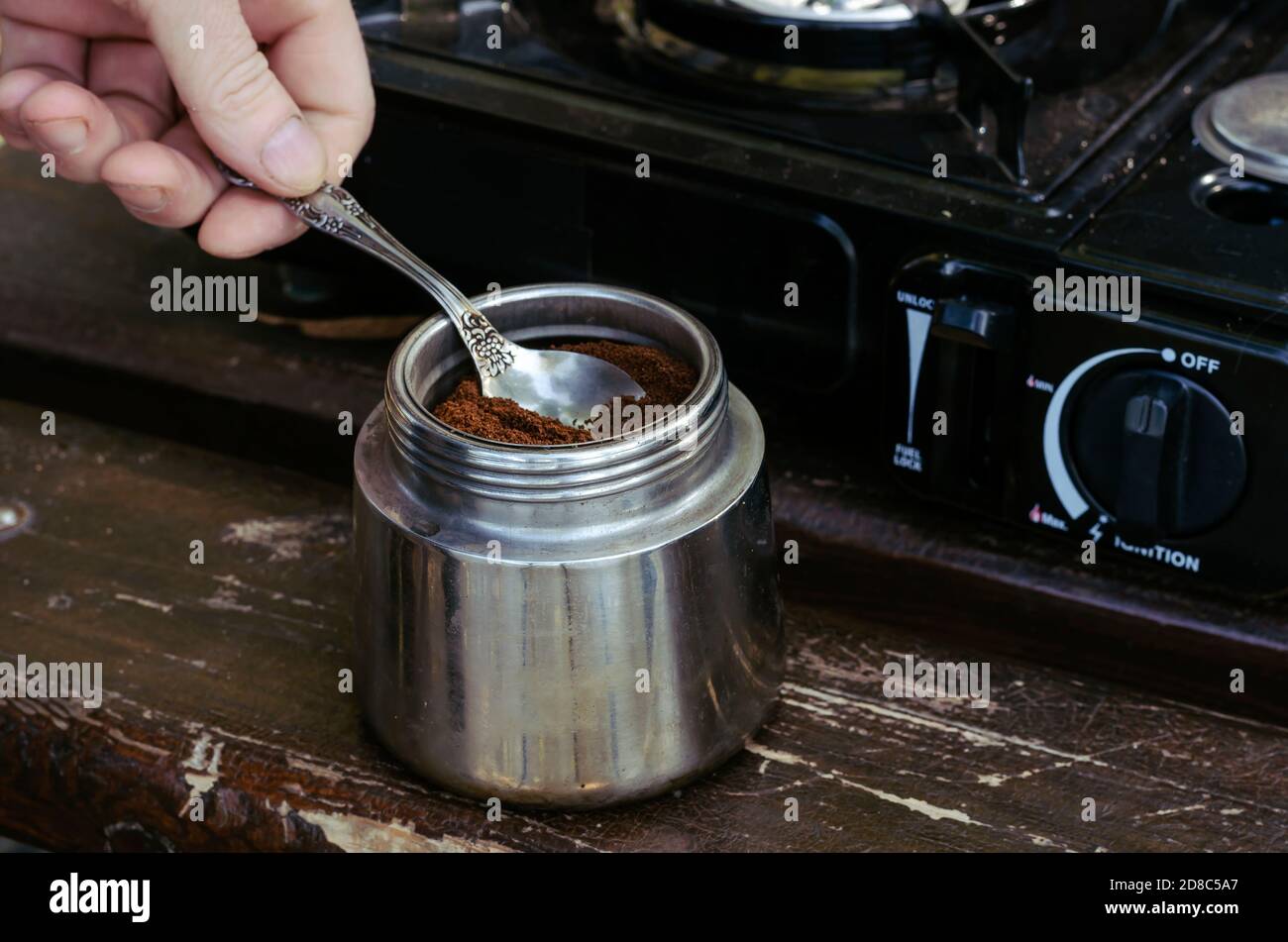 Cafetera, café, cuchara y cocina de gas portátil en el banco del parque.  Proceso de hacer café natural durante el picnic. Estilo de vida Fotografía  de stock - Alamy