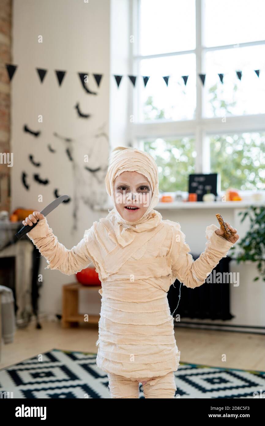 Retrato de niño lindo en momia disfraz de pie con cuchillo Y la galleta  como símbolo de la tradición del truco-o-trato para Halloween Fotografía de  stock - Alamy