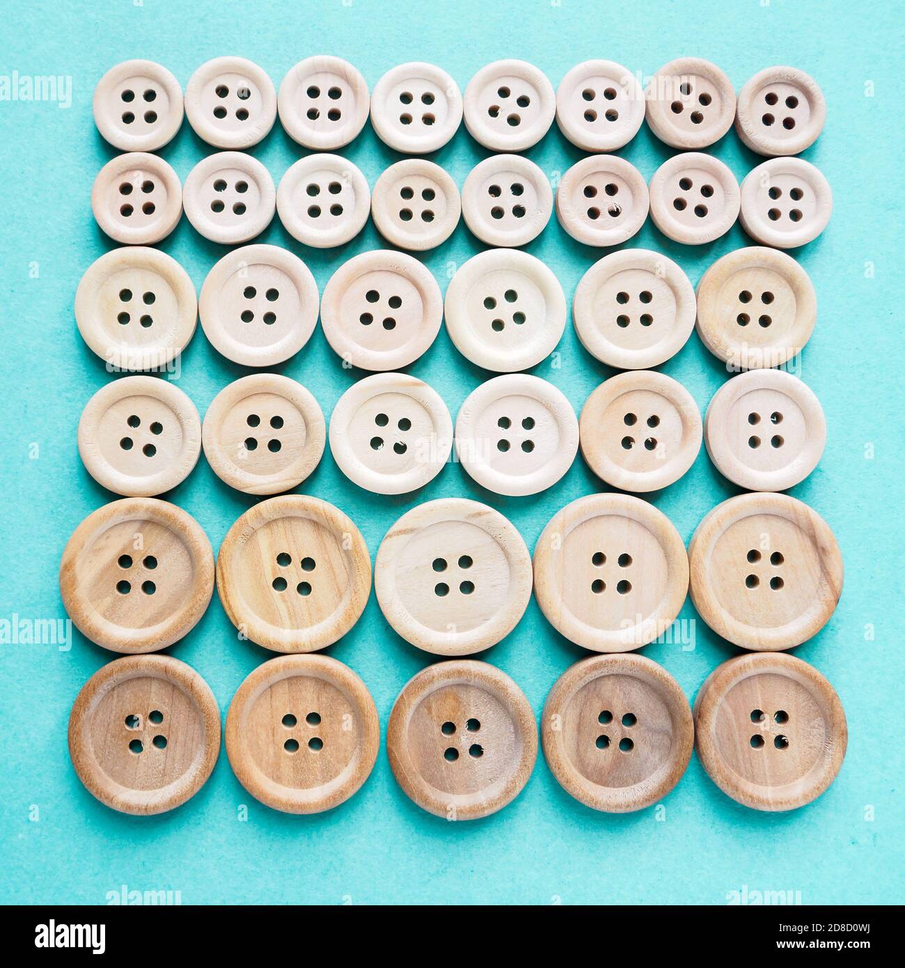 grupo de botones grandes y pequeños de madera beige en fila sobre fondo  azul Fotografía de stock - Alamy
