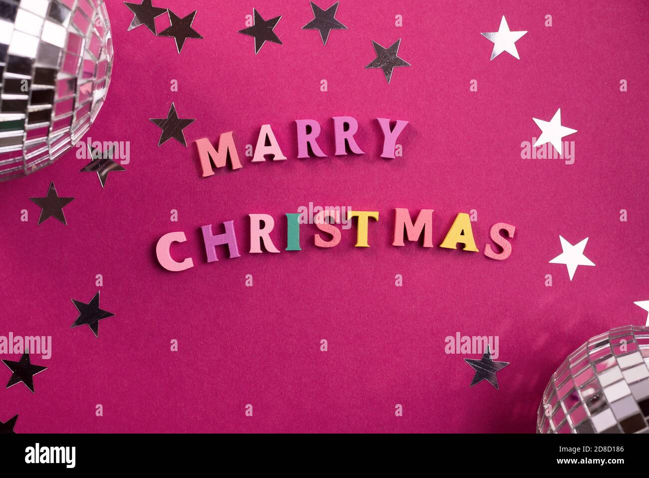 Feliz Navidad palabras de bienvenida hechas de cartas de madera, sobre un  fondo púrpura decorado con estrellas confeti, y mini bolas disco Fotografía  de stock - Alamy