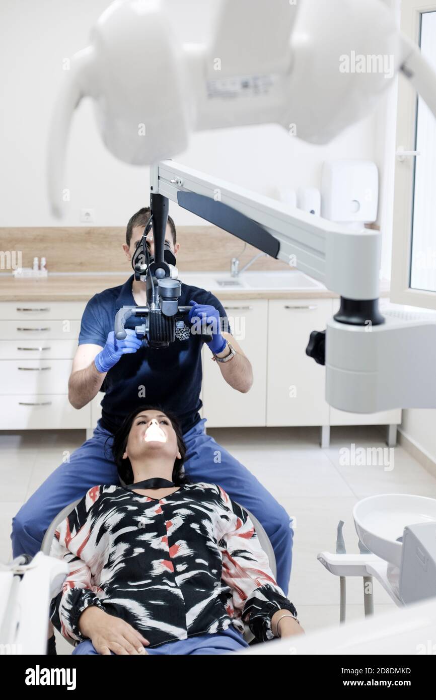 Dentista en el trabajo usando microscopio dental Foto de stock