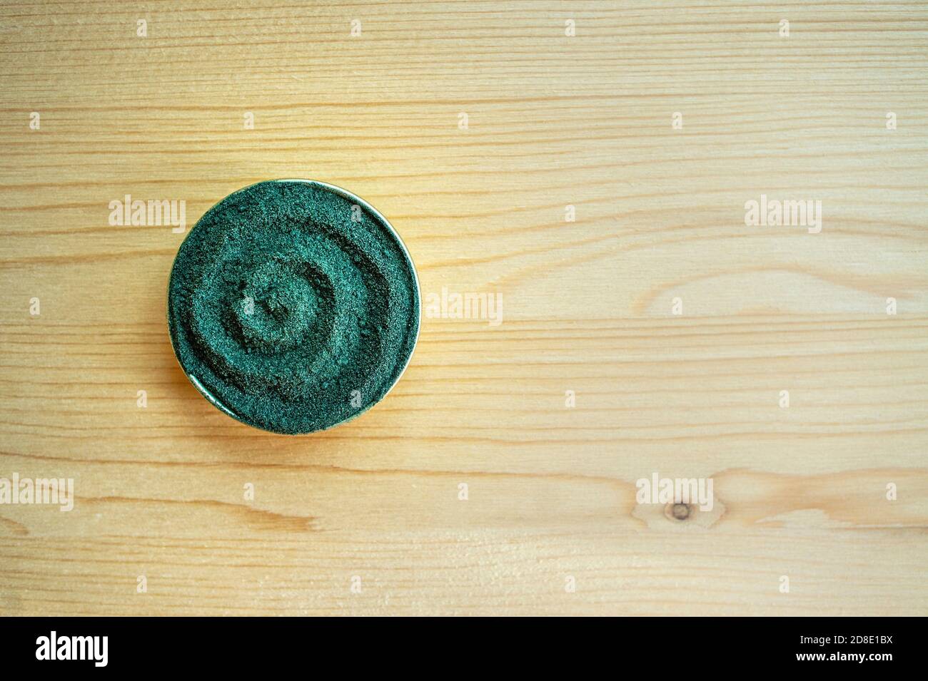 Polvo de chlorella o espirulina en forma de espiral sobre fondo de madera claro con espacio para copias Foto de stock