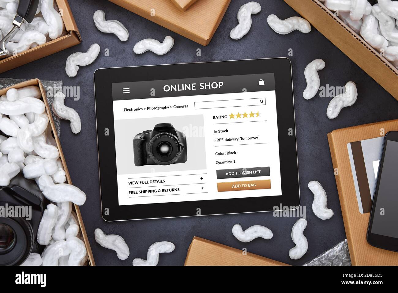 Compras en línea de productos electrónicos concepto. Tablet ordenador con la aplicación de la tienda en línea en la pantalla rodeada de cajas de cartón y paquetes en la parte trasera negra Foto de stock