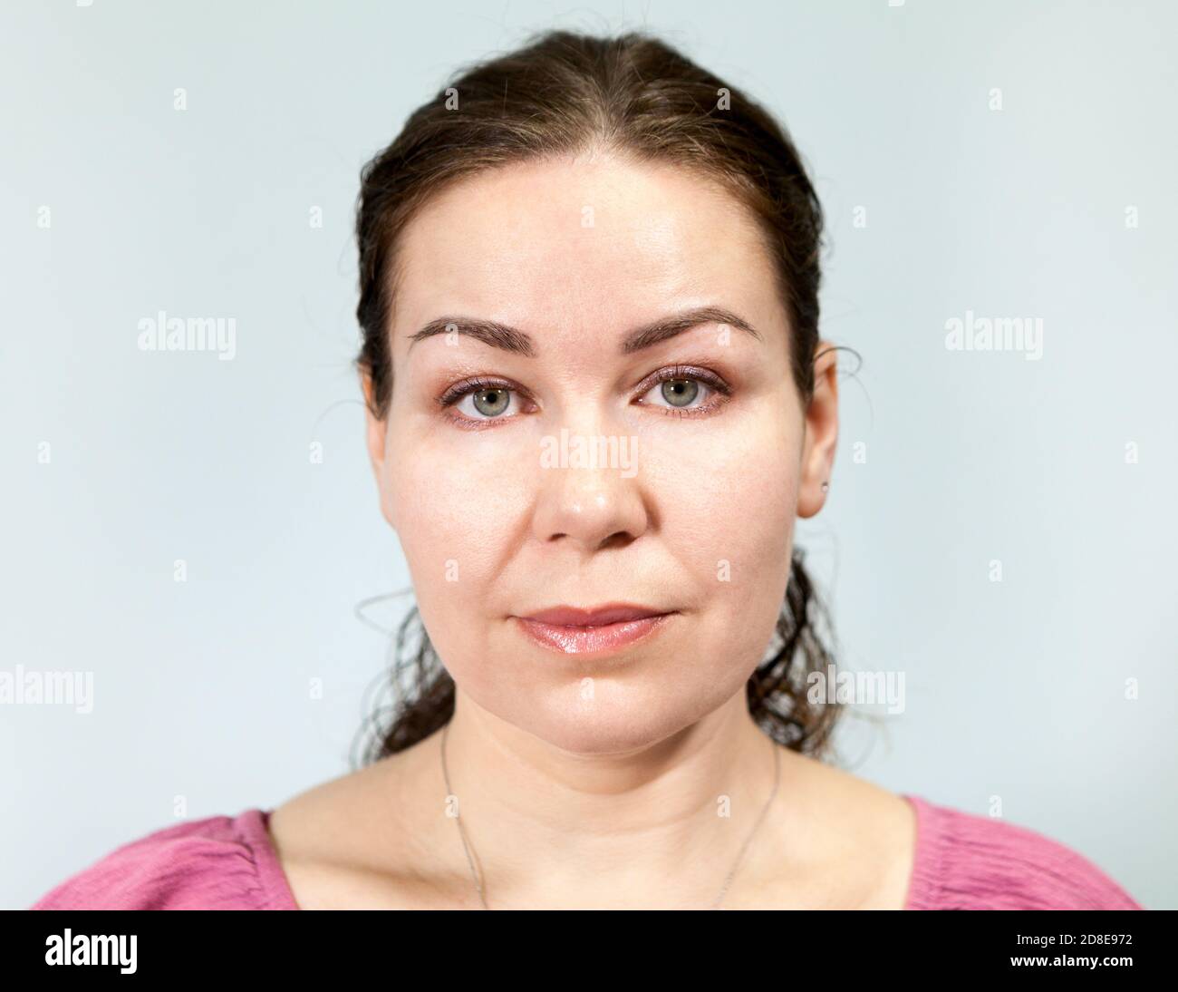 Retrato de una mujer con una expresión neutral, fondo gris, serie de emociones Foto de stock