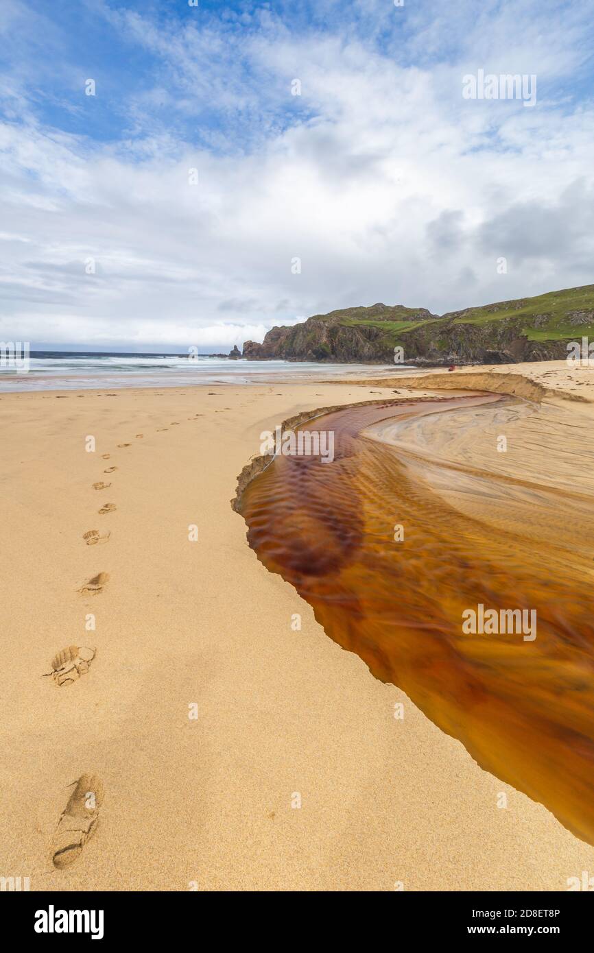 El río rojo corre hasta la playa de Dalmore en el Isla de Lewis Foto de stock