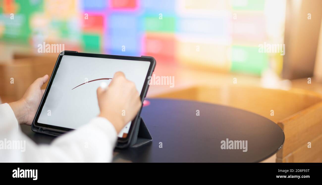 La mano femenina utilizando una tableta digital con pantalla táctil de  lápiz para dibujar en la mesa de trabajo de escritorio en el espacio de  trabajo conjunto para el nuevo concepto normal