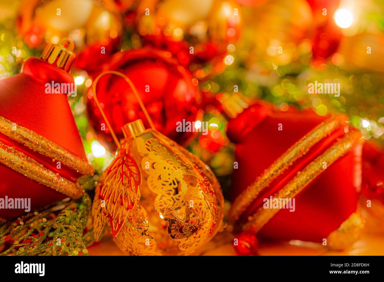 Adorno de Navidad en color dorado es finamente detallado y está rodeado de adornos de enfoque suave en colores brillantes. Foto de stock