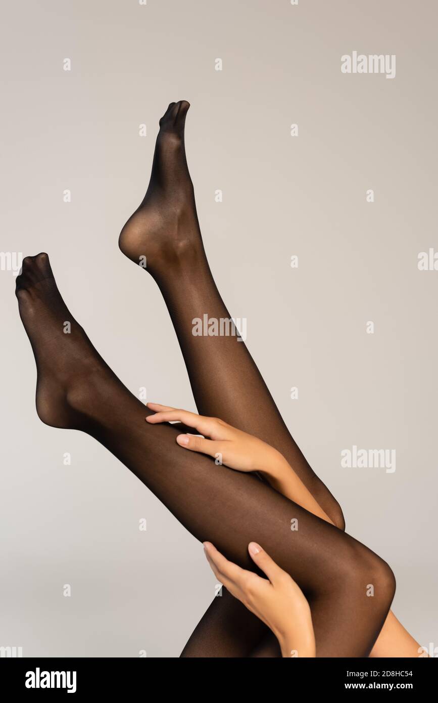 Vista recortada de la mujer con las piernas en el aire, con medias negras  aisladas en gris Fotografía de stock - Alamy