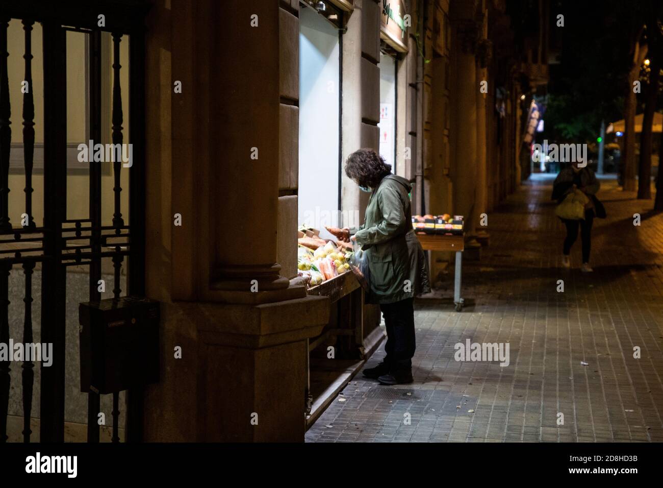 Barcelona, España. 2020.10.29. Una mujer hace las compras en una tienda fuera de las horas establecidas para el cierre de tiendas según el toque de queda. Foto de stock