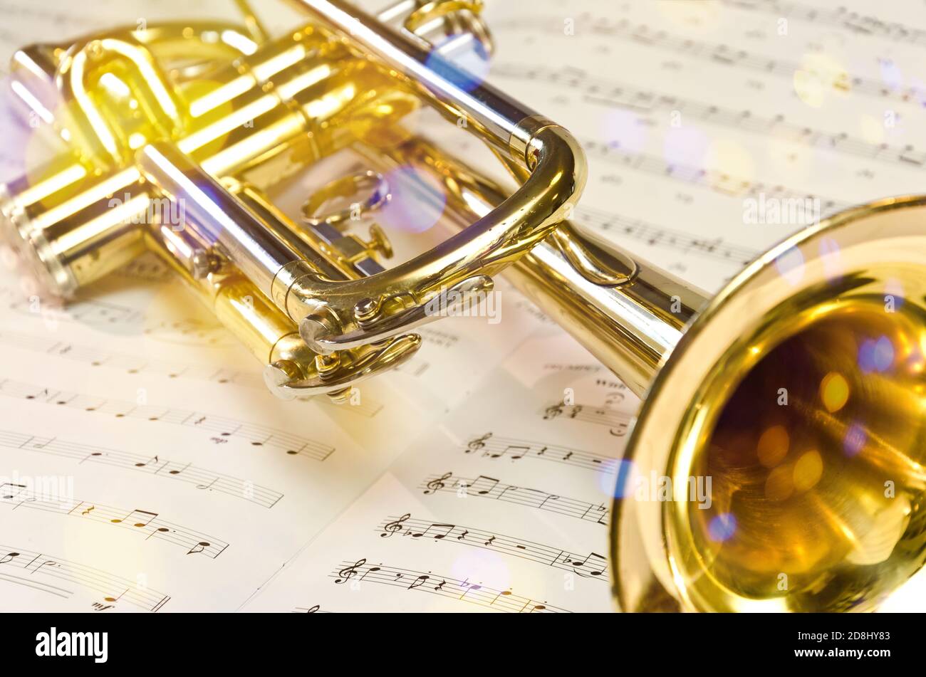 Trompeta de oro sobre partituras con reflejos escénicos y lentes llamarada Foto de stock