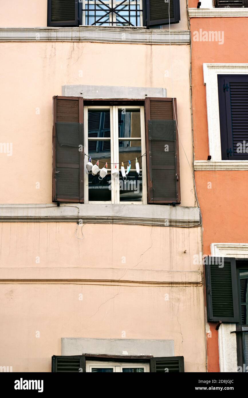 Máscaras médicas para covid 19 coronavirus colgado en la línea de lavandería, en un típico callejón romano, barrio Monti, Roma, Italia, Europa, Unión Europea, UE. Foto de stock