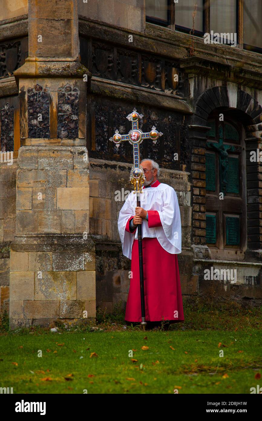 Norwich, Reino Unido 10/07/2012: Un sacerdote de iglesia anglicano en un manto rojo y blanco oeste se ve fuera de una iglesia histórica. Lleva una larga c decorativa Foto de stock