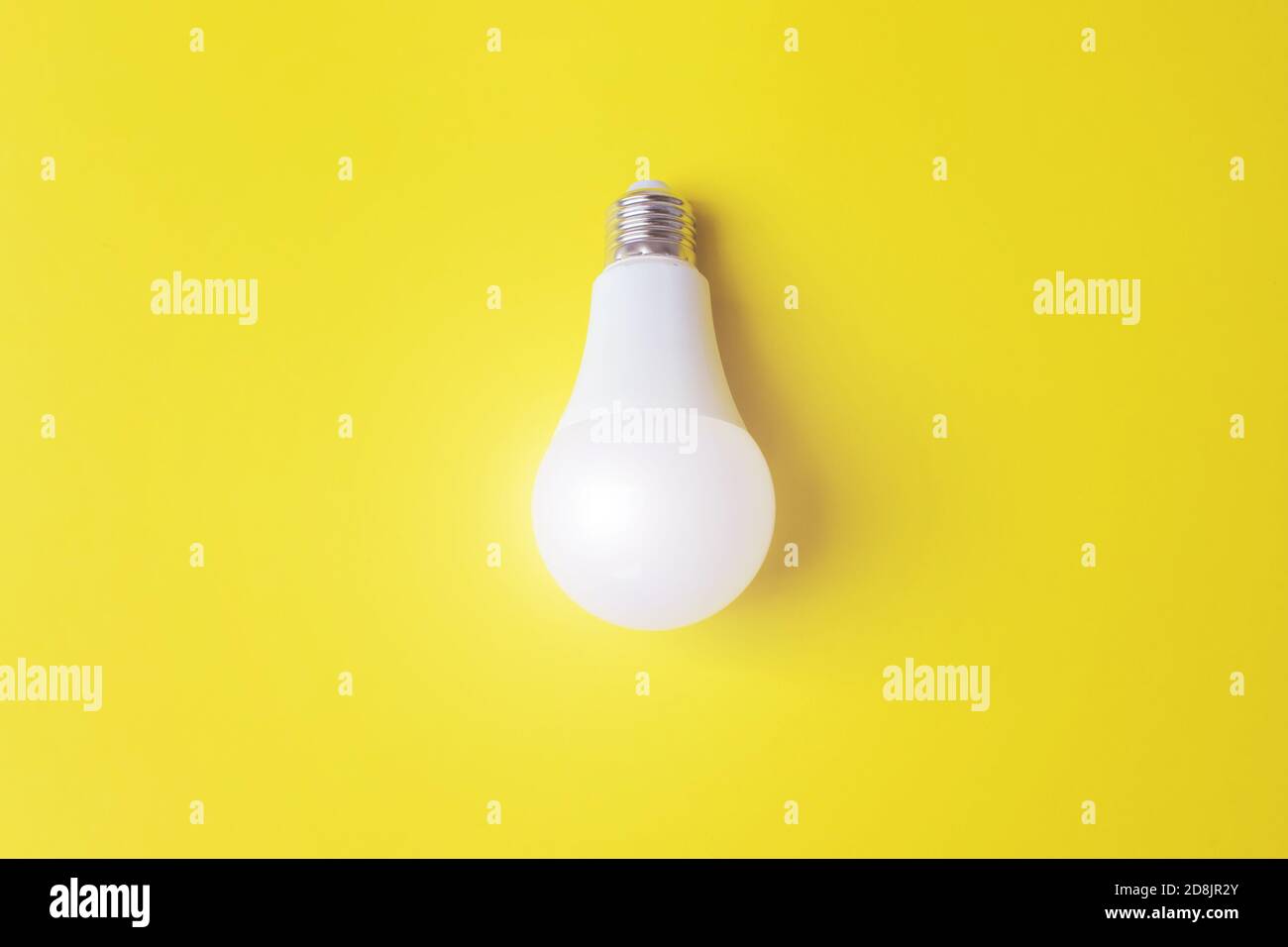 Bombilla de luz blanca brillante contra fondo amarillo . Idea, concepto de creatividad. Concepto de economía energética. Espacio de copia Foto de stock