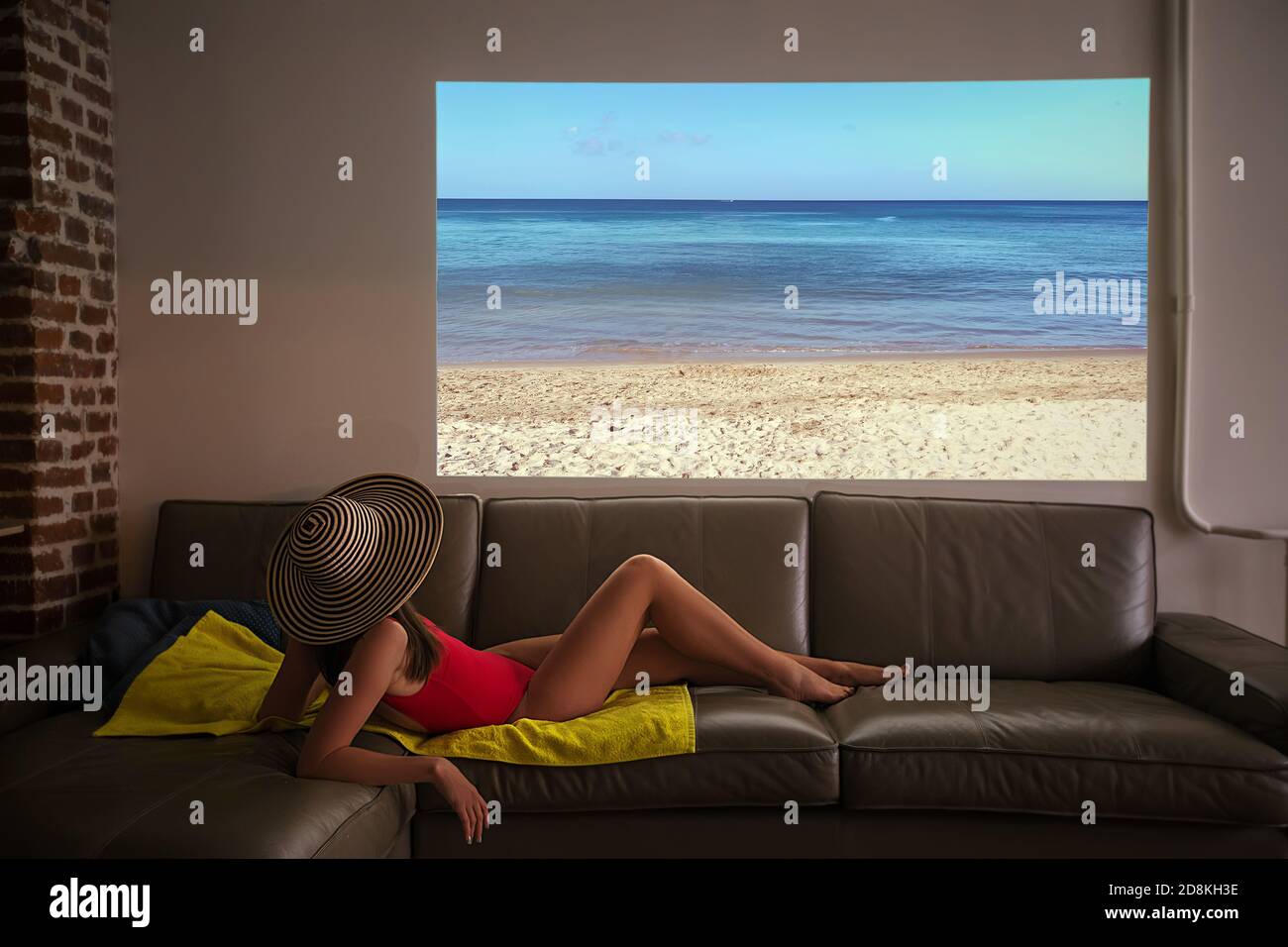 La mujer pretende tomar el sol en una playa falsa durante un pandemia en casa Foto de stock