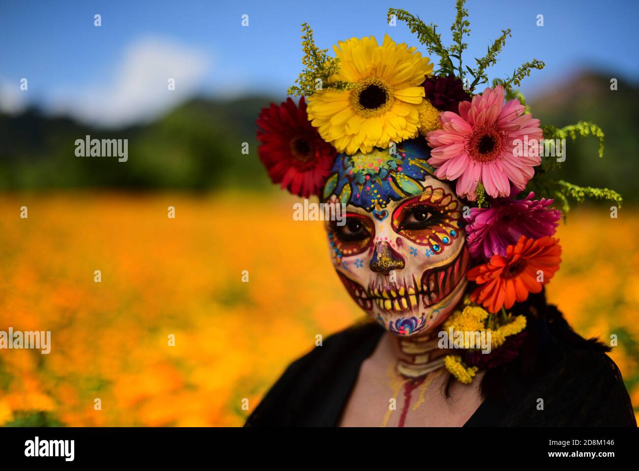NAOLINCO, MÉXICO - OCTUBRE 29: Una mujer vestida con un vestido negro y hecha como la catrina tradicional, con flores en la cabeza, mira la cámara mientras posas para un fotoshoot, en NAOLINCO, MÉXICO - OCTUBRE 29: Una mujer vestida con un vestido negro y hecha como la catrina tradicional, con flores en la cabeza, mira la cámara mientras posas para un fotoshoot, en
