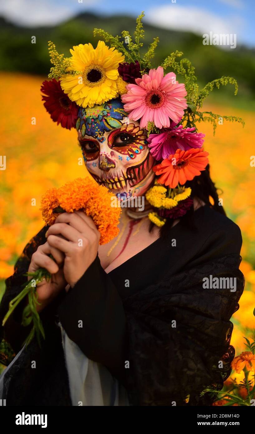 NAOLINCO, MÉXICO - OCTUBRE 29: Una mujer vestida con un vestido negro y hecha como la catrina tradicional, con flores en la cabeza, mira la cámara mientras posas para un fotoshoot, en NAOLINCO, MÉXICO - OCTUBRE 29: Una mujer vestida con un vestido negro y hecha como la catrina tradicional, con flores en la cabeza, mira la cámara mientras posas para un fotoshoot, en