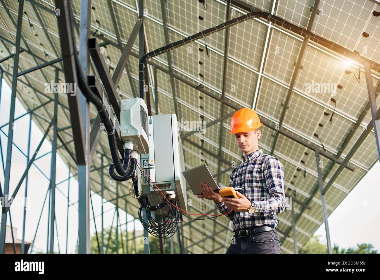 Ingeniero masculino trabajando con el ordenador portátil y el sensor, en el fondo de la central solar. Paneles solares, electricidad solar. Futuro de la innovación. Tecnología moderna. Foto de stock
