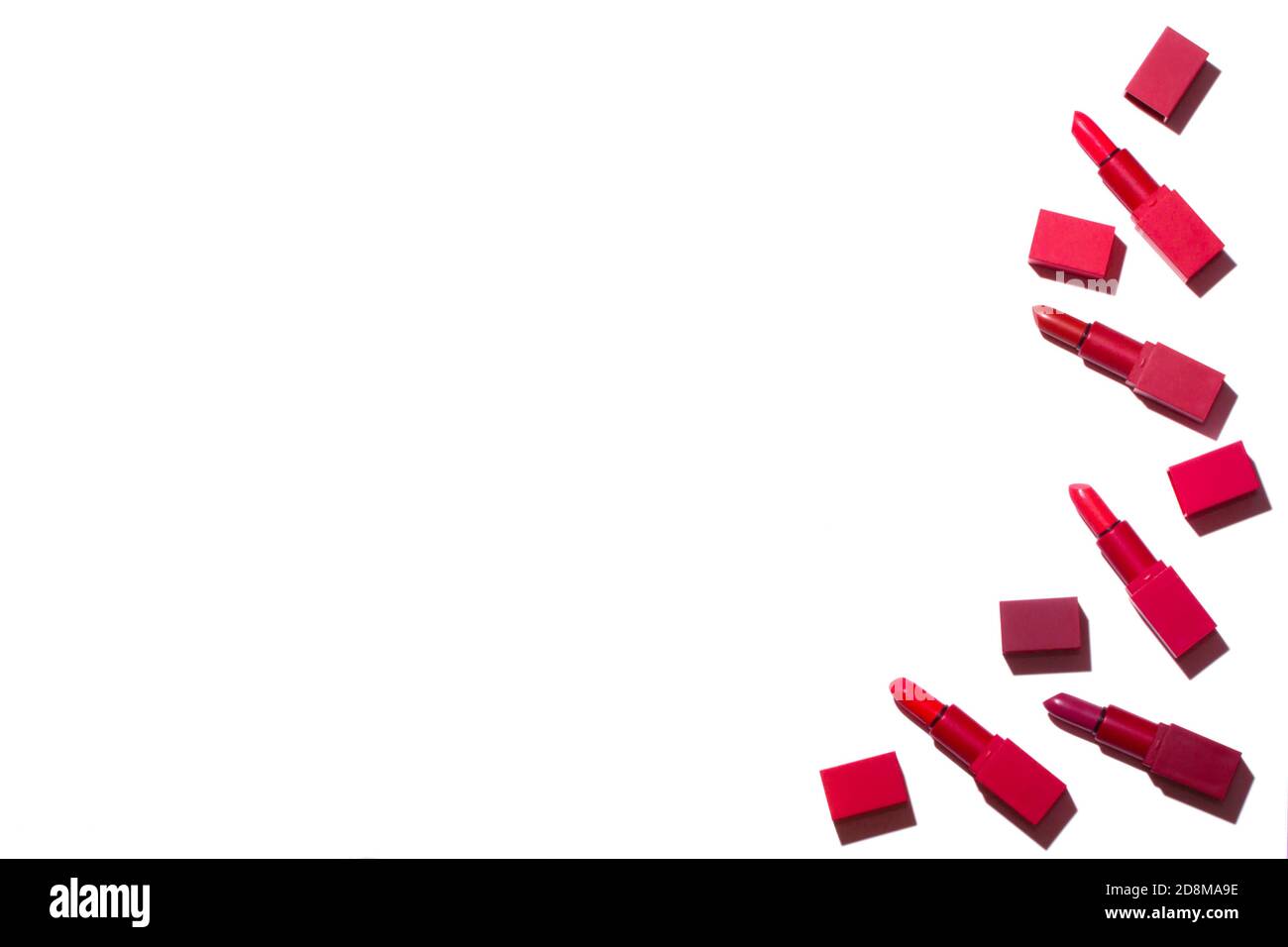 Grupo de lápices labiales rojo extendido sobre un fondo blanco. A la derecha hay un lugar para una inscripción. Foto de stock