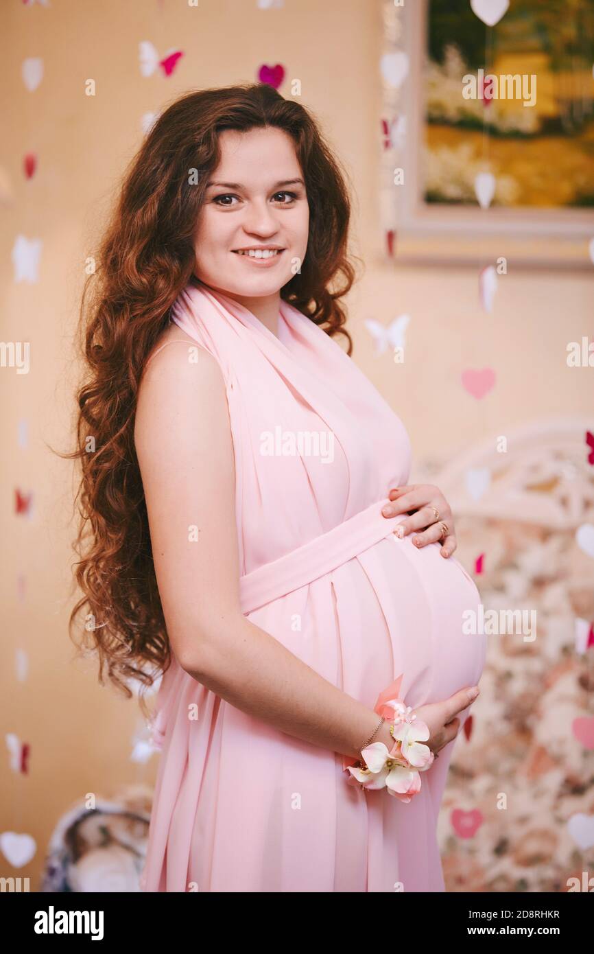 Joven hermosa mujer embarazada con pelo largo rojo en un delicado boudoir  rosa vestido largo. Moda para mujeres embarazadas. Maternidad feliz  Fotografía de stock - Alamy