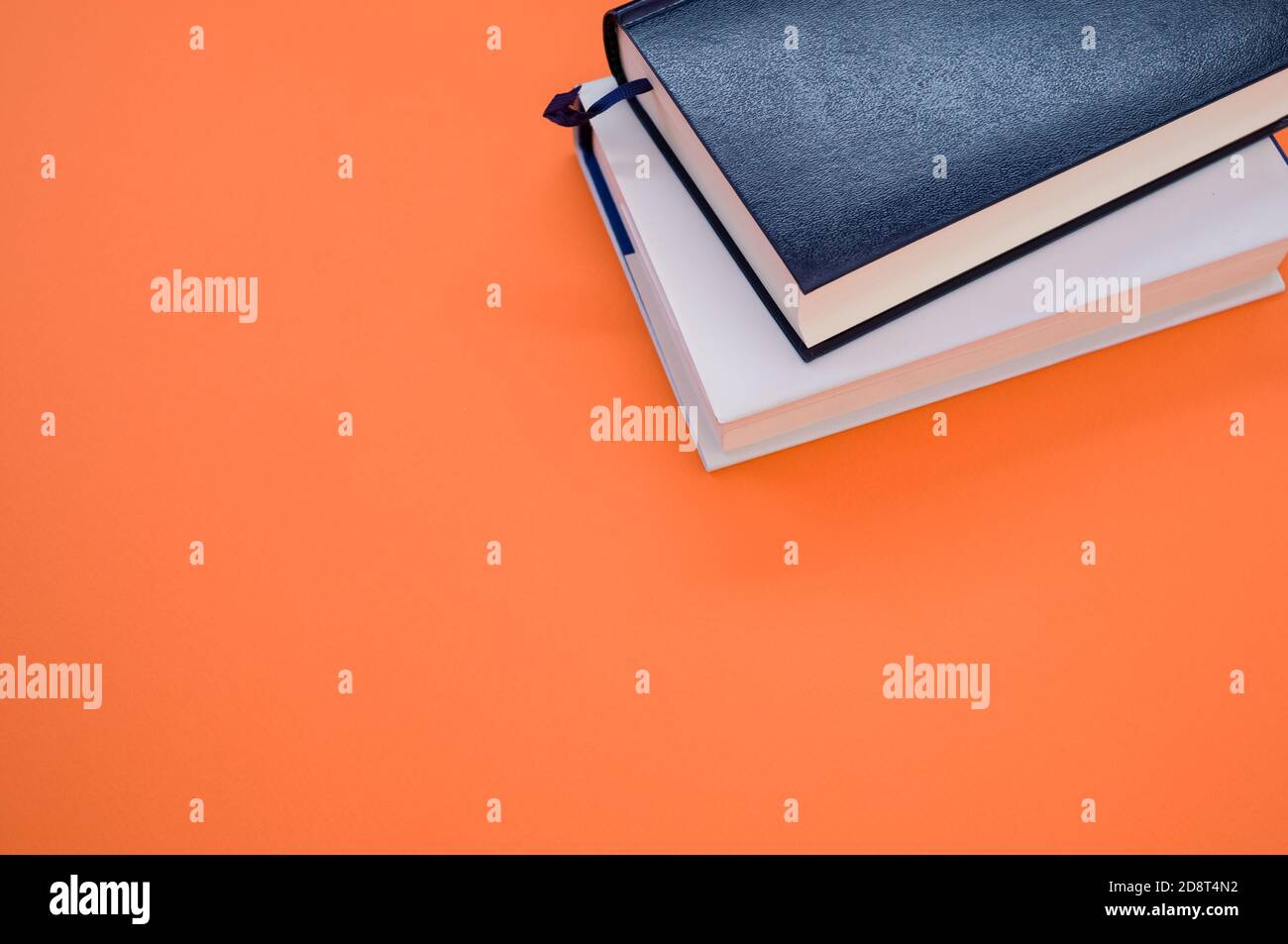 Tiro de libros de gran ángulo sobre una superficie naranja Foto de stock