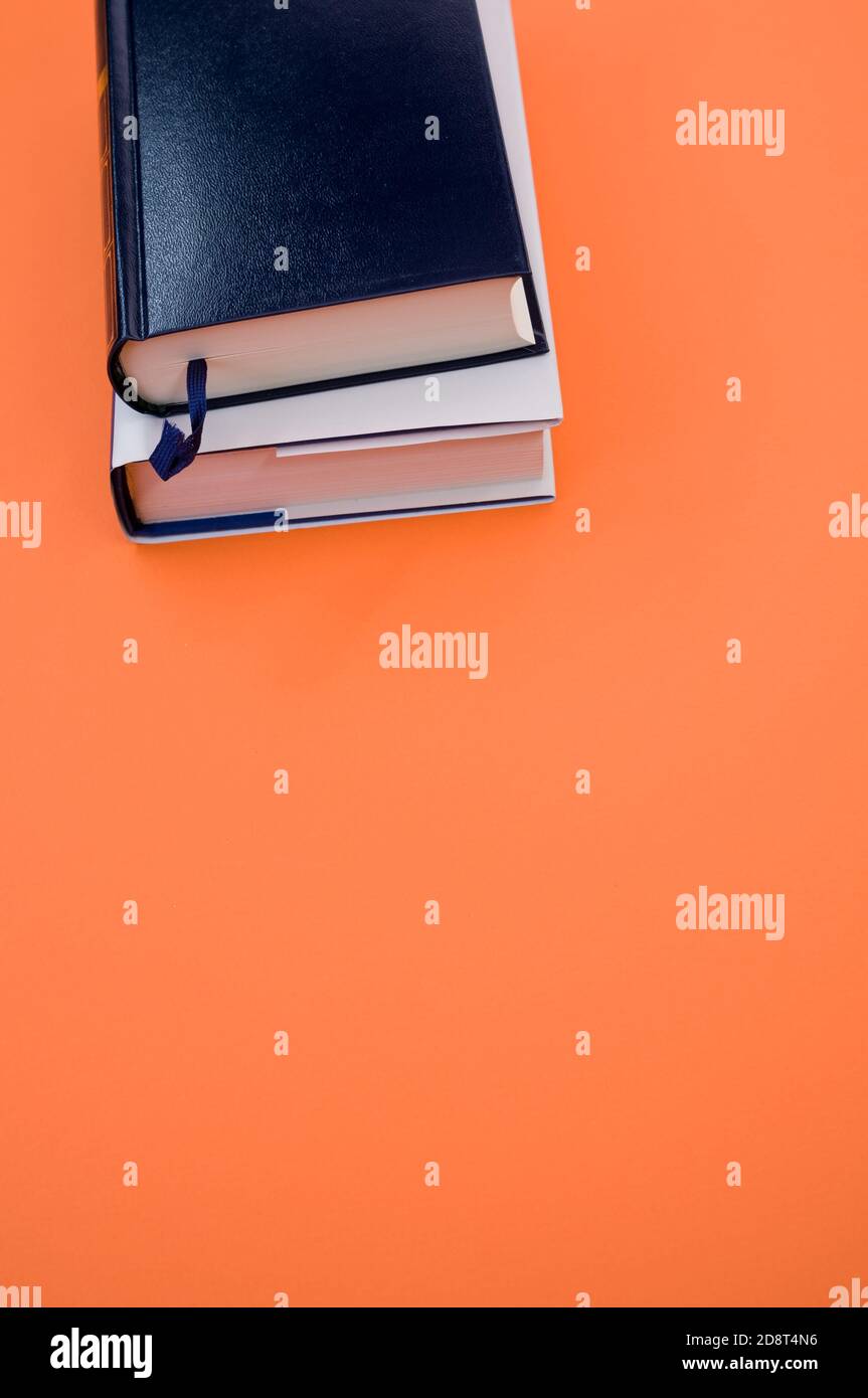 Tiro vertical de libros sobre una superficie naranja Foto de stock