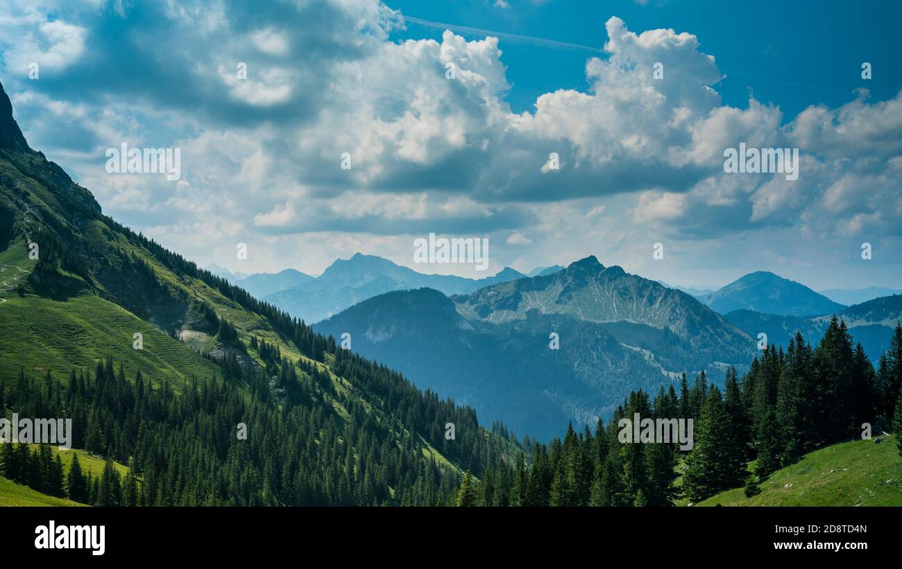 Alemania, Allgaeu, Breitenberg impresionantes montañas altas y árboles verdes que cubren un paisaje natural sin fin con cielo nublado Foto de stock