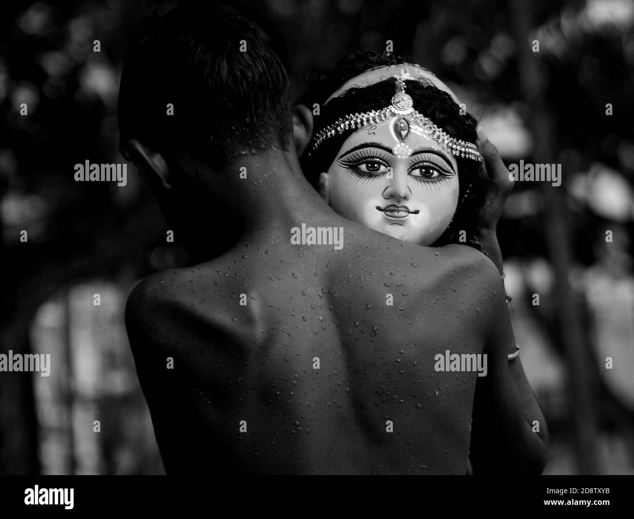Un niño sostiene la cabeza de un ídolo de la diosa Durga durante una ceremonia de inmersión para Dashami, el último día del festival Durga Puja. El festival es el mayor evento religioso para los hindúes bengalíes. Los hindúes creen que la diosa Durga simboliza el poder y el triunfo del bien sobre el mal. Agartala, Tripura, India. Foto de stock