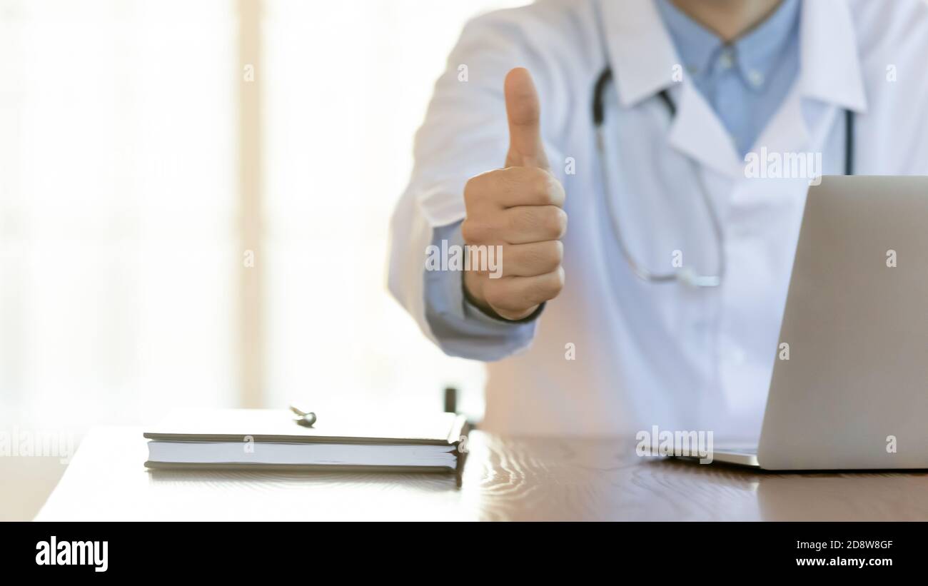 Médico masculino mostrando el gesto de pulgar hacia arriba aconsejando el mejor servicio hospitalario Foto de stock