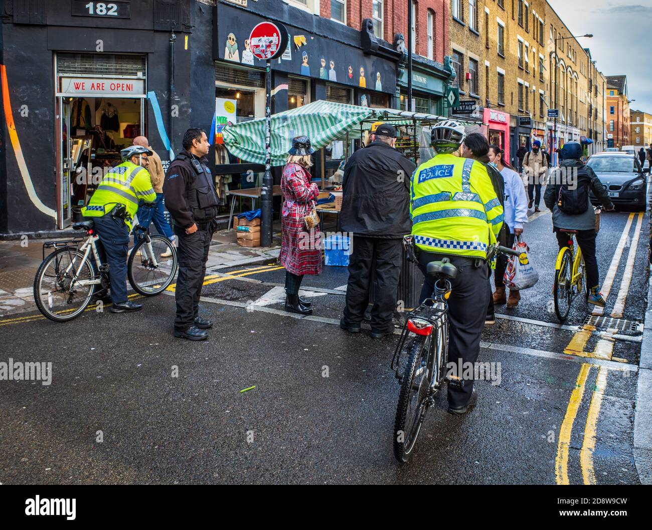 Cumplimiento del mercado de Londres - el personal de los mercados de la policía y de la torre de los hambets hace cumplir las regulaciones de venta de mercado en el mercado de Brick Lane, este de Londres. Foto de stock